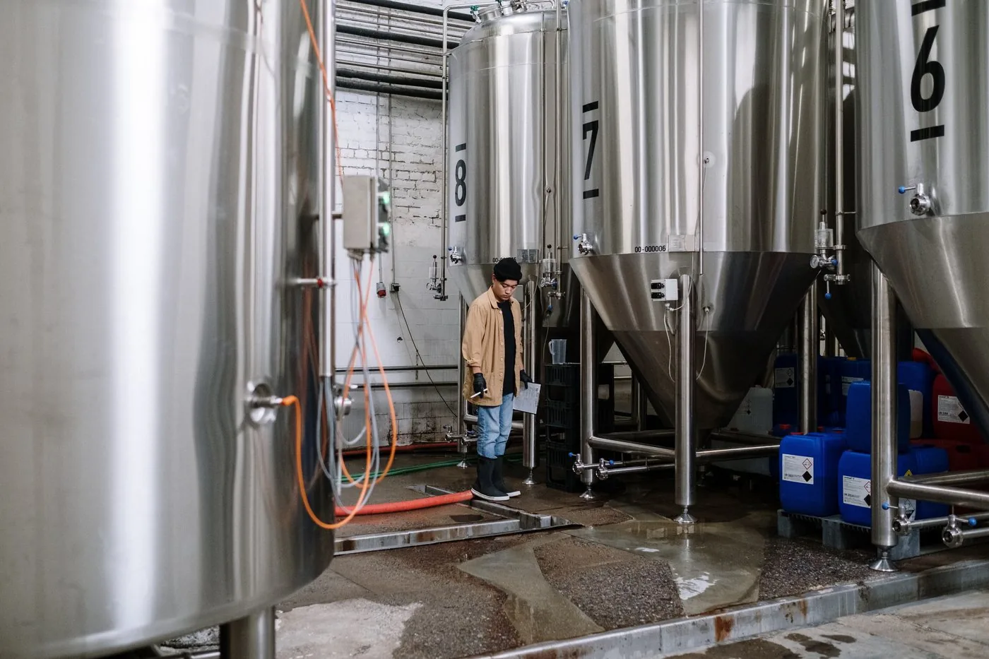 A brewer inspecting fermentation tanks on the production floor