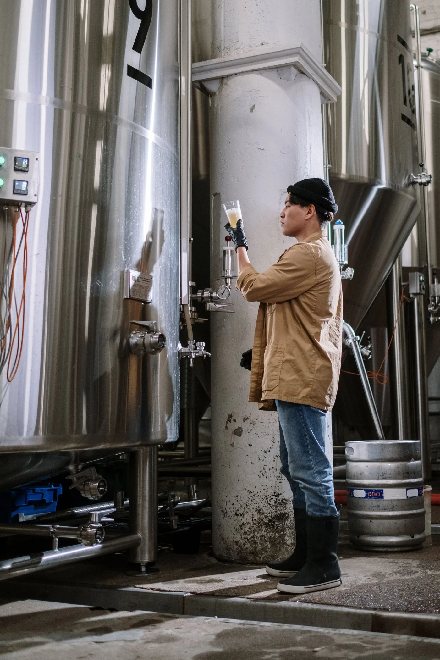 A brewer checking a stainless steel fermenter